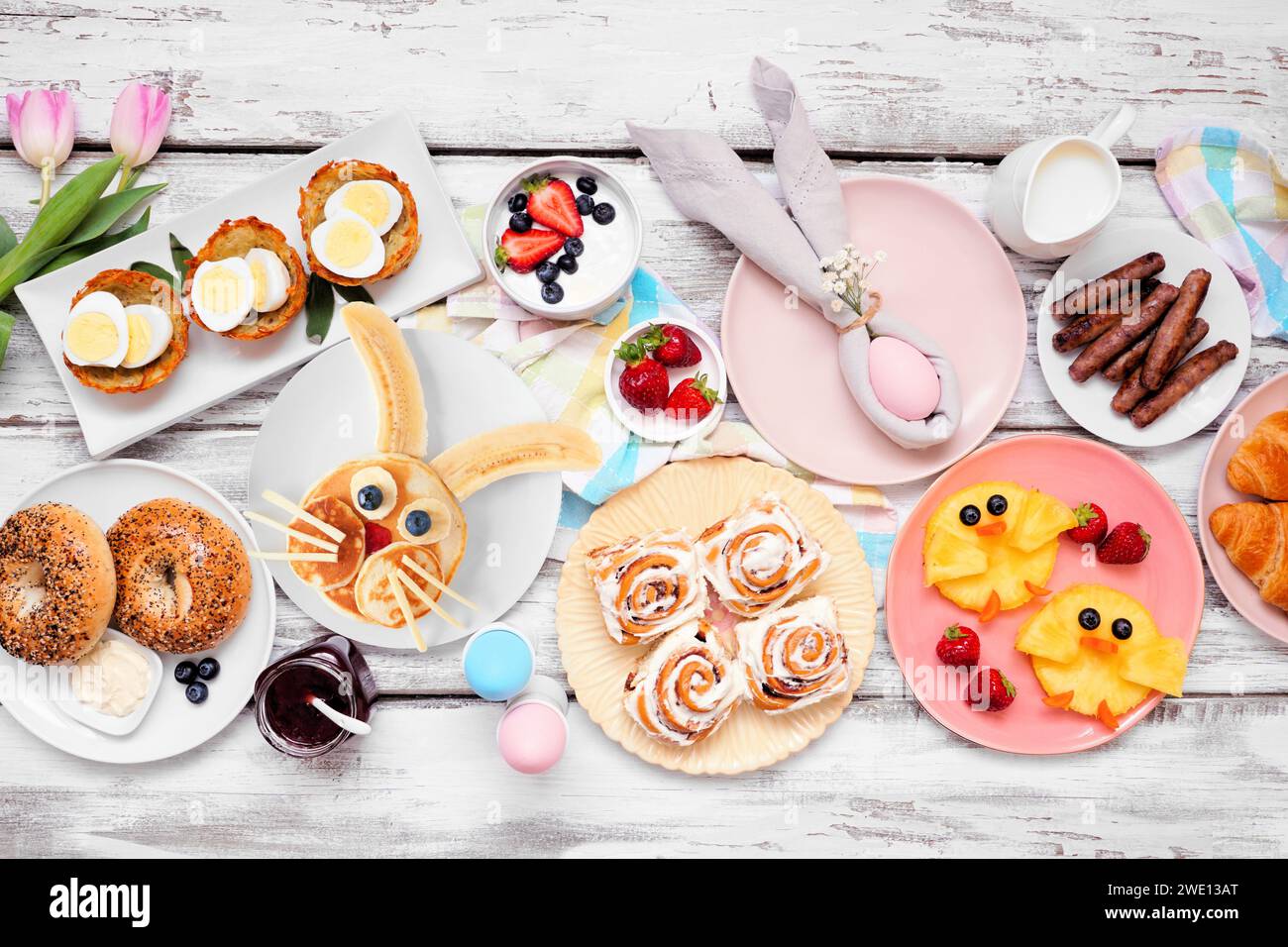 Osterfrühstück oder Brunch-Tisch. Blick über dem Zimmer auf weißem Holzhintergrund. Hasenpfannkuchen, Eiernester, Hühnerfrüchte und verschiedene Frühlingsspeisen Stockfoto
