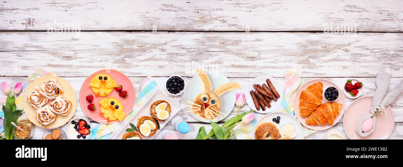 Osterfrühstück oder Brunch am unteren Rand. Draufsicht auf weißem Holzbanner Hintergrund. Hasenpfannkuchen, Eiernester, Hühnerfrucht und eine Auswahl an Sprossen Stockfoto