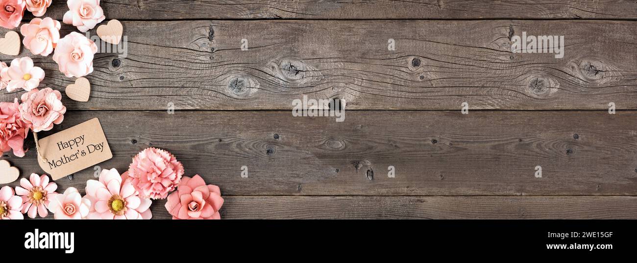 Eckrand zum Happy Mothers Day mit Papierblumen und Geschenkanhänger. Blick von oben vor einem rustikalen Holzbanner Hintergrund. Kopierbereich. Stockfoto