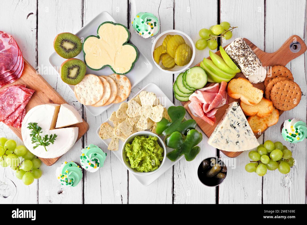 Die Esstisch-Szene mit dem Thema St. Patricks Day vor weißem Holzhintergrund. Sammlung von Käse-, Fleisch-, Obst- und Gemüsevorspeisen. Von oben nach unten VI Stockfoto