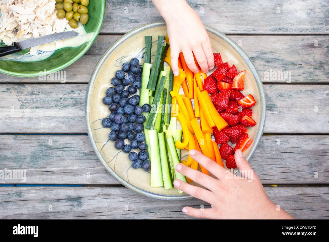 Gesunder Teller mit Obst und Gemüse auf einem Tisch im Freien, der einen Sommerabend genießt. Stockfoto