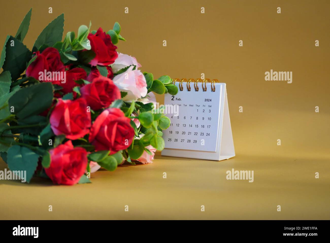 Schreibtischkalender für Februar 2024 auf goldenem Hintergrund mit Rosen. Stockfoto