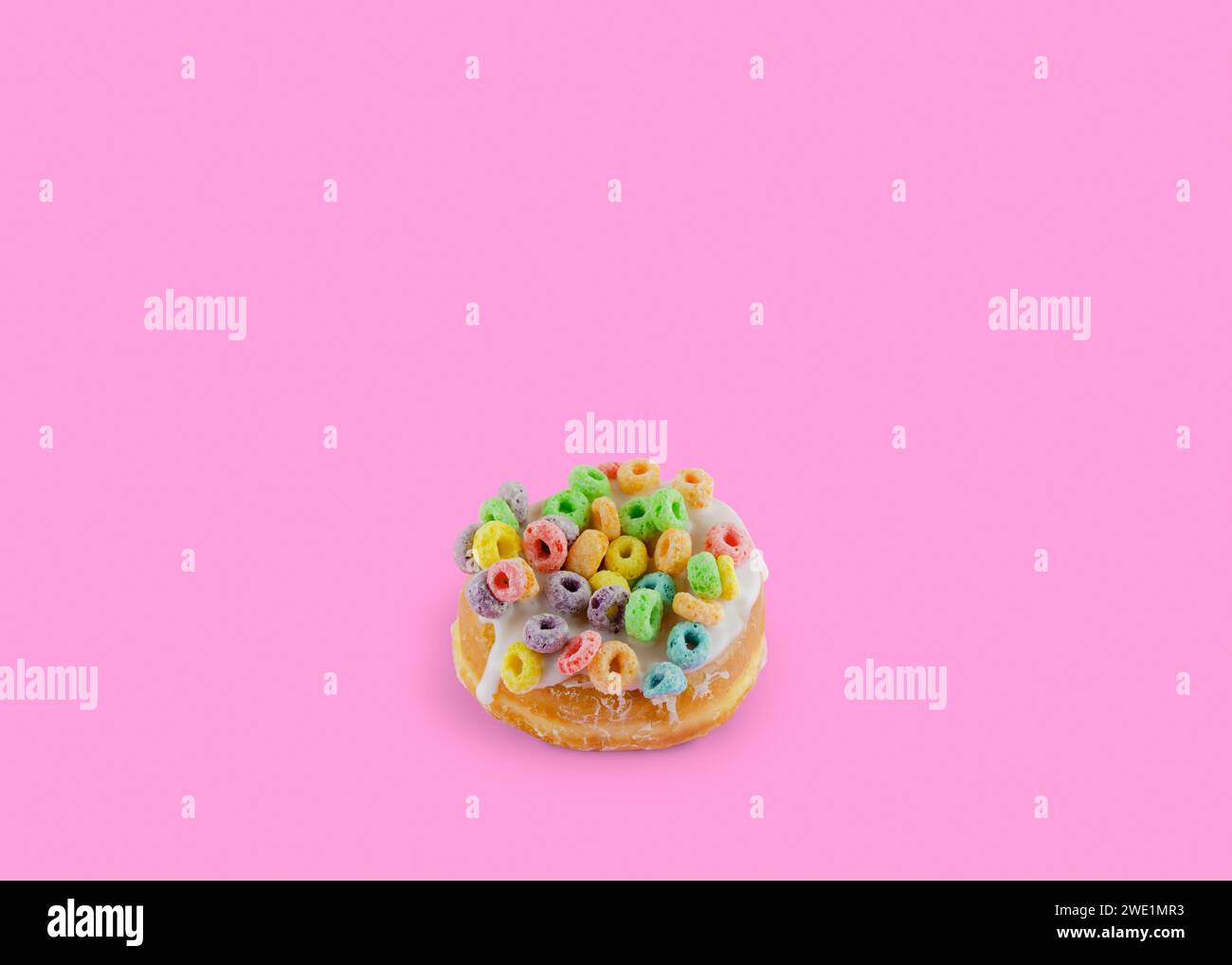 Rosafarbener Donut mit buntem Schleifenbrei auf rosafarbenem Hintergrund mit Kopierraum Stockfoto