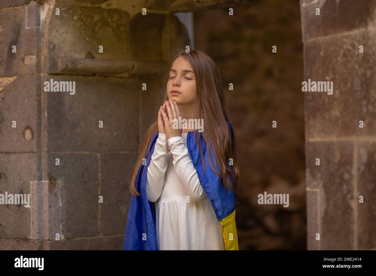 Mädchen betend in ukrainische Flagge gewickelt. Stockfoto