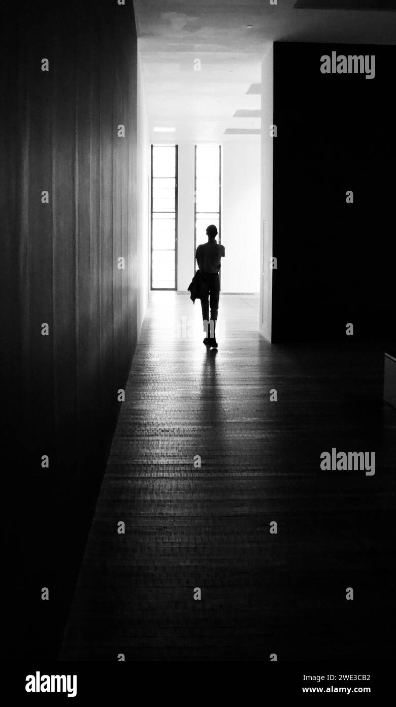 Einsame Person, die zwischen dem Ausstellungsraum spaziert, ist modern in Silhouette festgehalten. Stockfoto