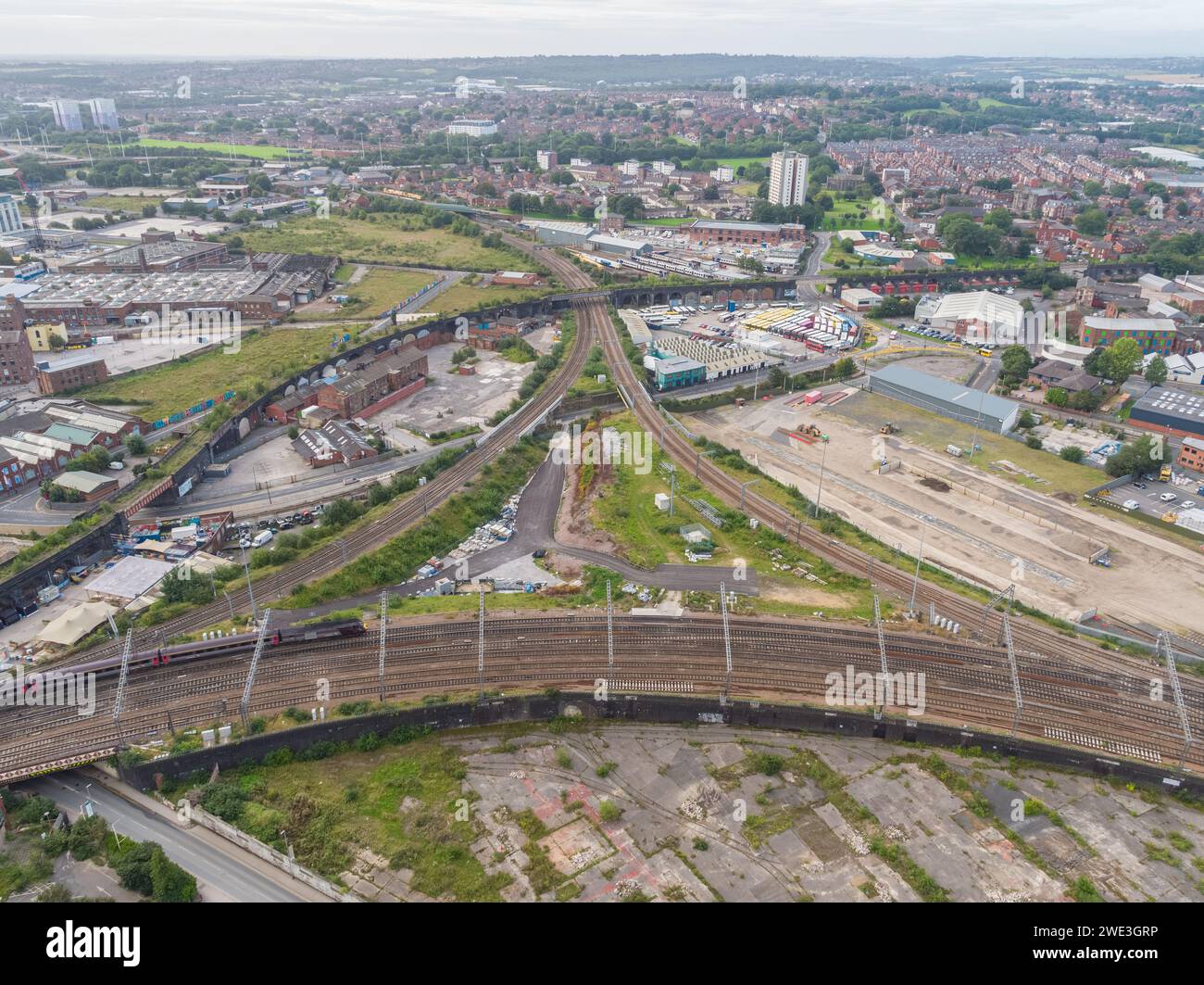 Luftaufnahme eines Zuges auf der Hauptstrecke in/aus dem Bahnhof Leeds mit Nebenlinien in Richtung Westen und einem stillgelegten Viadukt und einer Brücke Stockfoto
