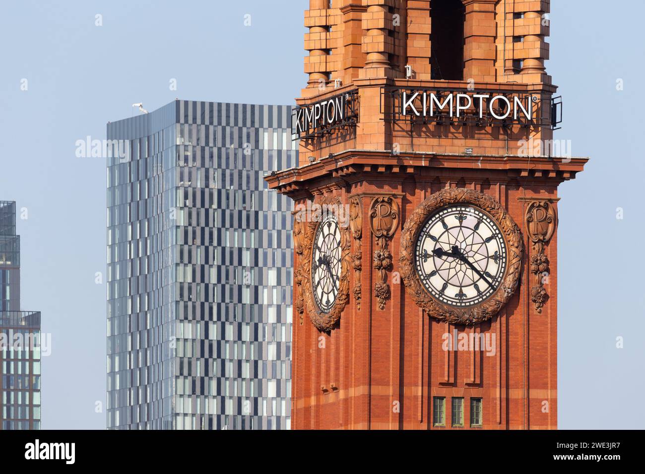 Zoomtes Nahbild des berühmten Kimpton Uhrenturms in Manchester, Großbritannien, mit dem Wohnturm am Deansgate Square im Hintergrund Stockfoto