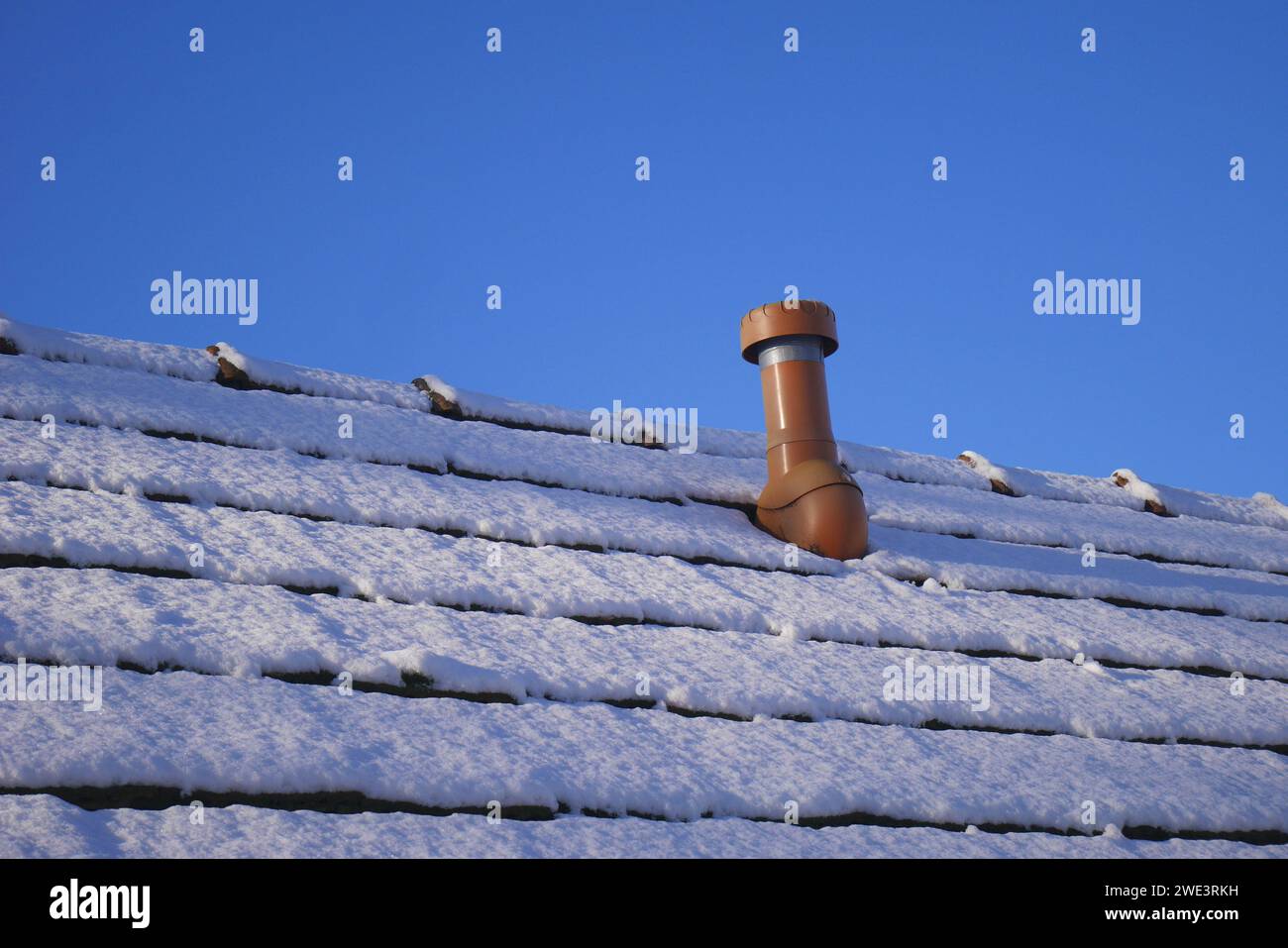 Schornstein und schneebedecktes Dach eines Bauernhauses vor blauem Himmel, Szigethalom, Ungarn Stockfoto