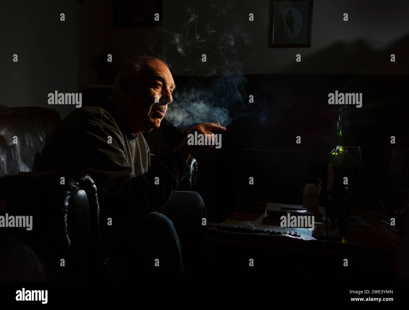 Ein Mann, der eine gerollte Zigarette in einem dunklen Raum raucht Stockfoto