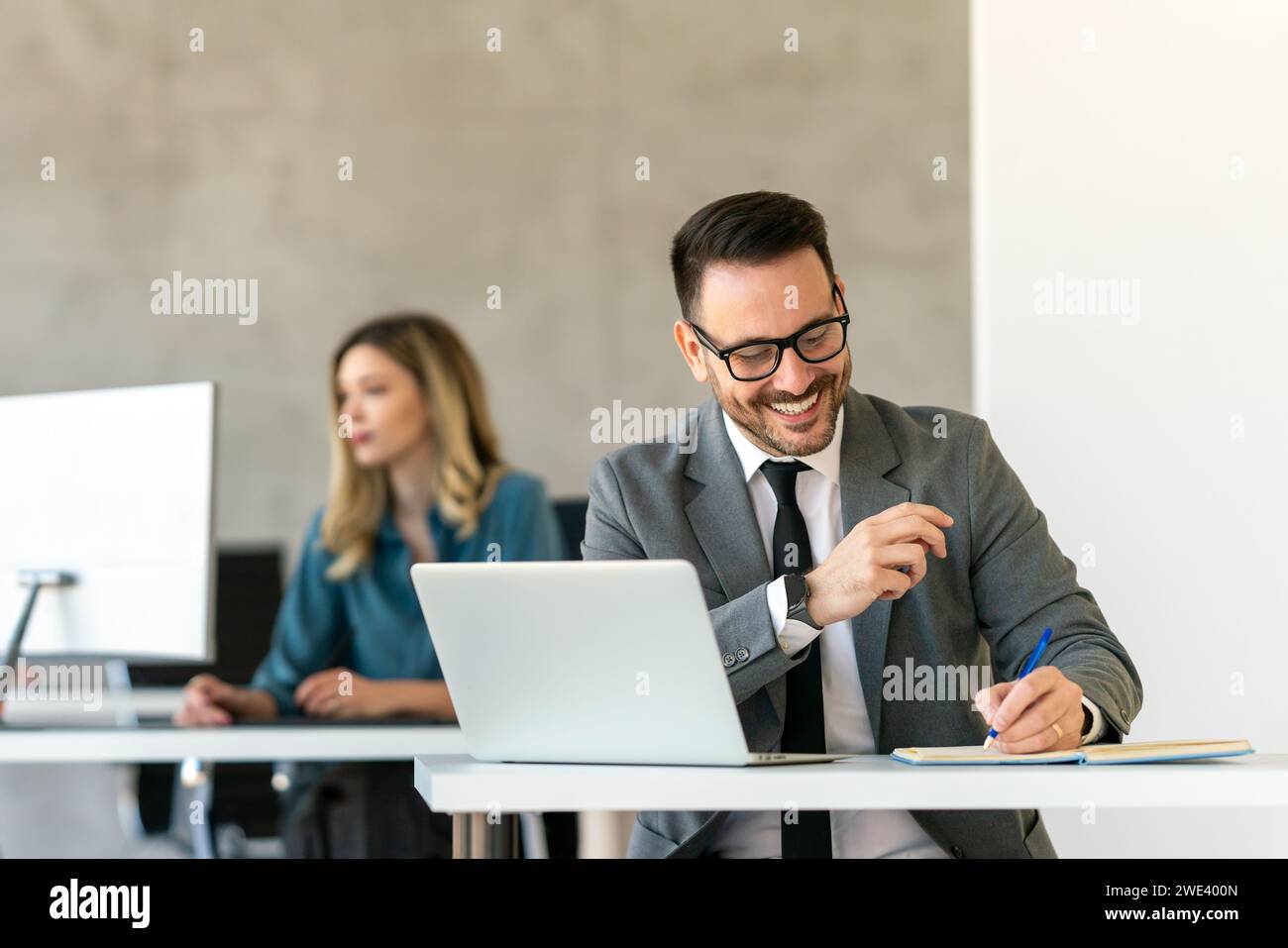 Junger Geschäftsmann mit Laptop im Büro. Der Manager denkt über erfolgreiche finanzielle Ideen nach. Stockfoto