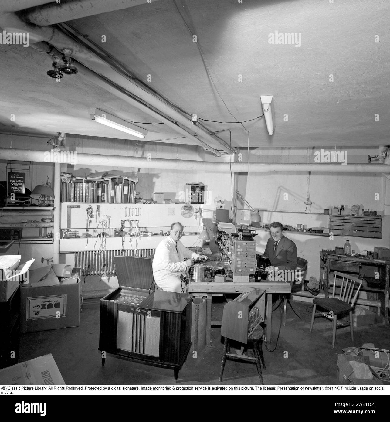 In den 1950er Jahren Innenraum eines Radio- und tv-Service-Shops, in dem Radios und Gramophone repariert und gewartet wurden. 1956. Conard Ref. 3210 Stockfoto