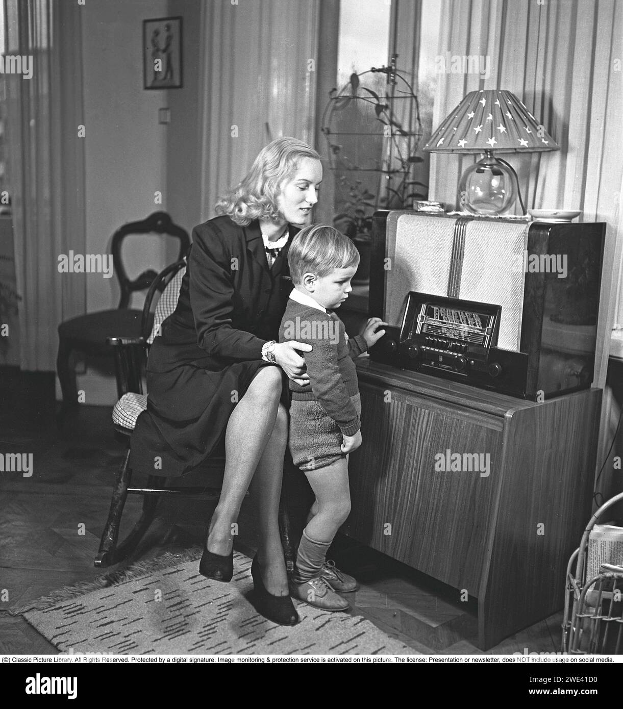 Radio in den 1940ern Eine Mutter und ihr Sohn hören Radio. Neben den UKW-Übertragungen lokaler Radiosender wurden auch ausländische Radiosender auf Langwelle gehört. 1946. Krisotffersson Ref. Y16-6 Stockfoto