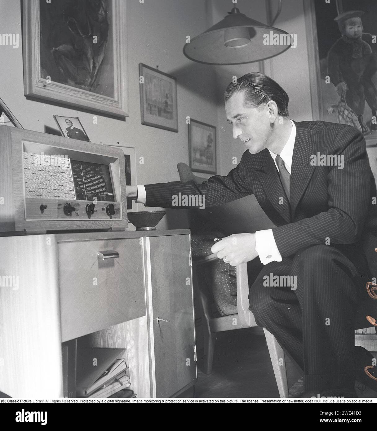 Radio in den 1940ern Ein gut gekleideter Mann in seinem Haus wird gesehen, wie er Radio hört. Er ist Lauritz Falk, 1909-1990, Schwedisch-norwegischer Schauspieler. 1946. Kristoffersson Ref. T63-5 Stockfoto