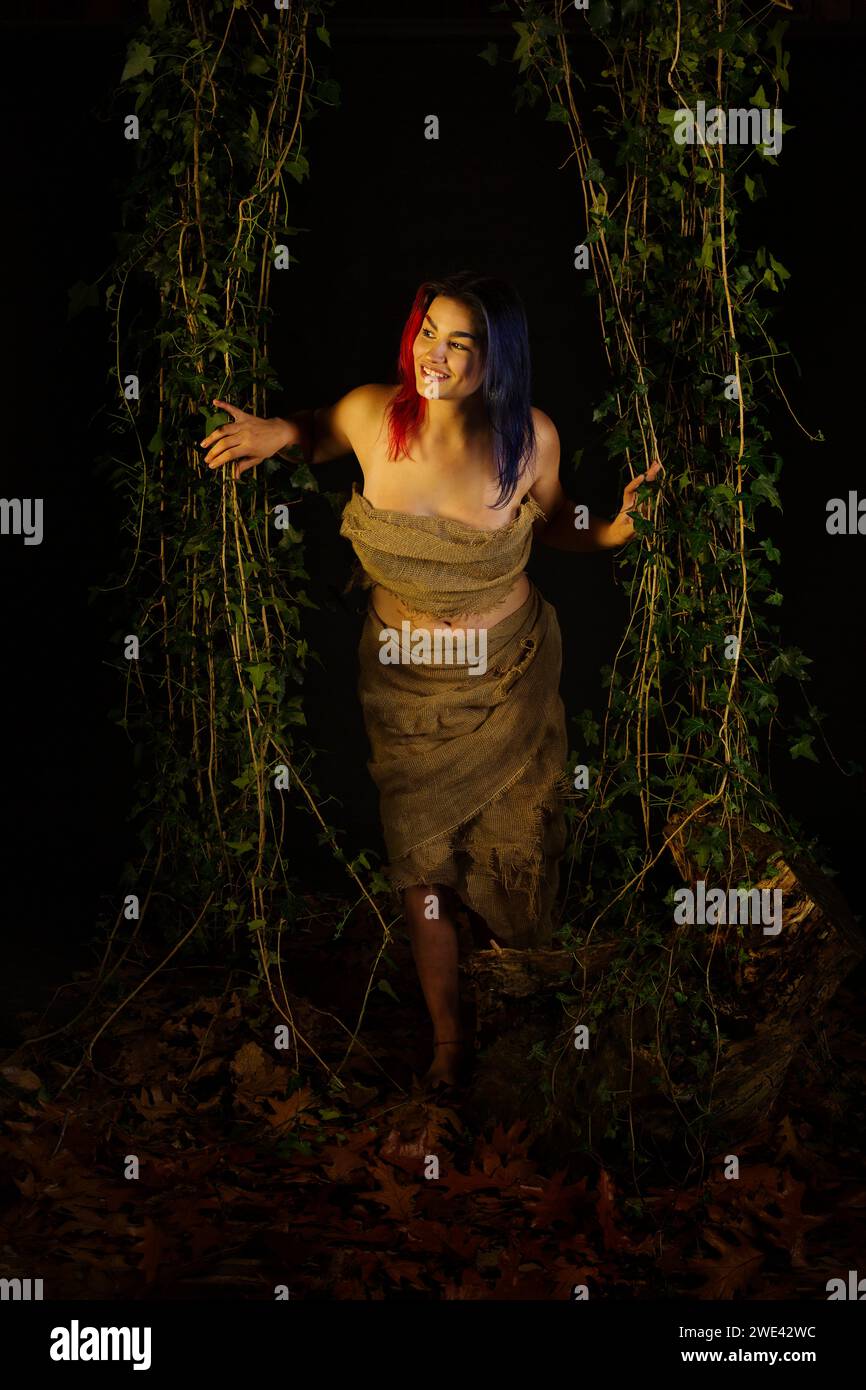 Hübsche Frau, die durch Efeu im Wald schaut Stockfoto