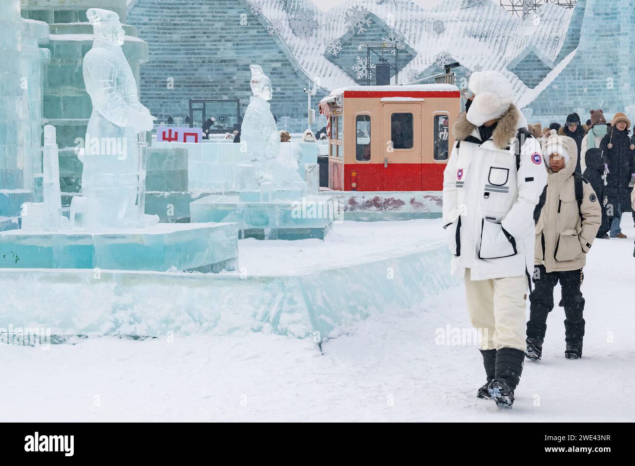 Harbin, Chinas Provinz Heilongjiang. Januar 2024. Besucher spazieren in der Nähe von Eisskulpturen der Terrakotta-Krieger in Harbin Ice and Snow World in Harbin, nordöstlicher chinesischer Provinz Heilongjiang, 23. Januar 2024. Als eine Gruppe von KI-generierten Bildern von Eisskulpturen der Terrakotta-Krieger im Internet viral wurde, schufen Künstler eine Reihe von Eisskulpturen der Terrakotta-Krieger in Harbin Ice and Snow World, um Besucher anzulocken. Quelle: Xie Jianfei/Xinhua/Alamy Live News Stockfoto