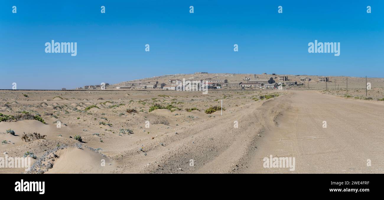 Stadtlandschaft mit Sandstraße und Bergbaugeisterstadt in der Wüste Sperrgebiet, aufgenommen im hellen Licht des späten Frühlings in Kolmanskop, Namibia, Afrika Stockfoto
