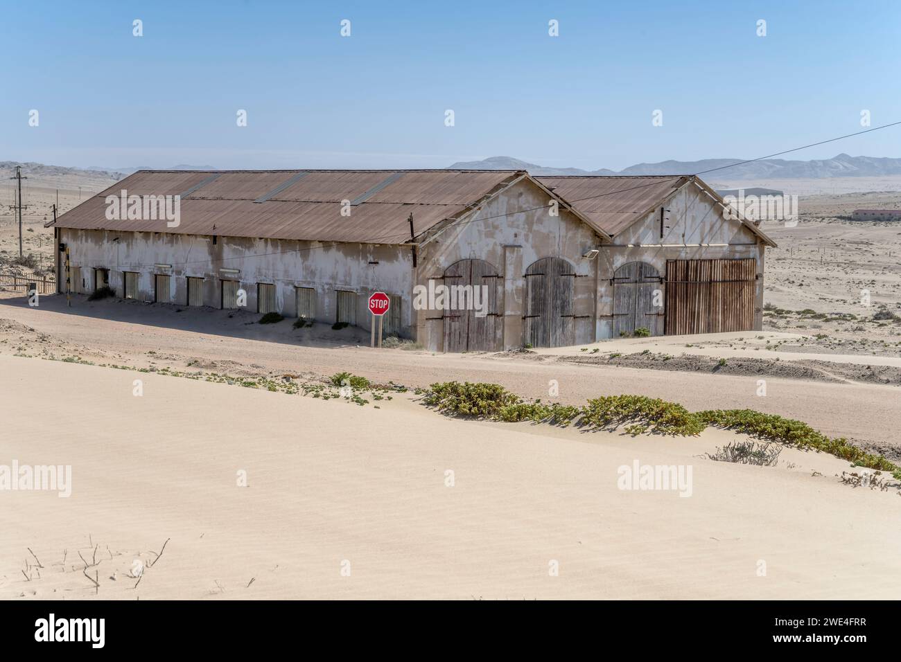 Stadtbild mit verlassenen Lagerhäusern auf Sand in einer Minengeisterstadt in der Wüste, aufgenommen im hellen Licht des späten Frühlings in Kolmanskop, Namibia, Afrika Stockfoto