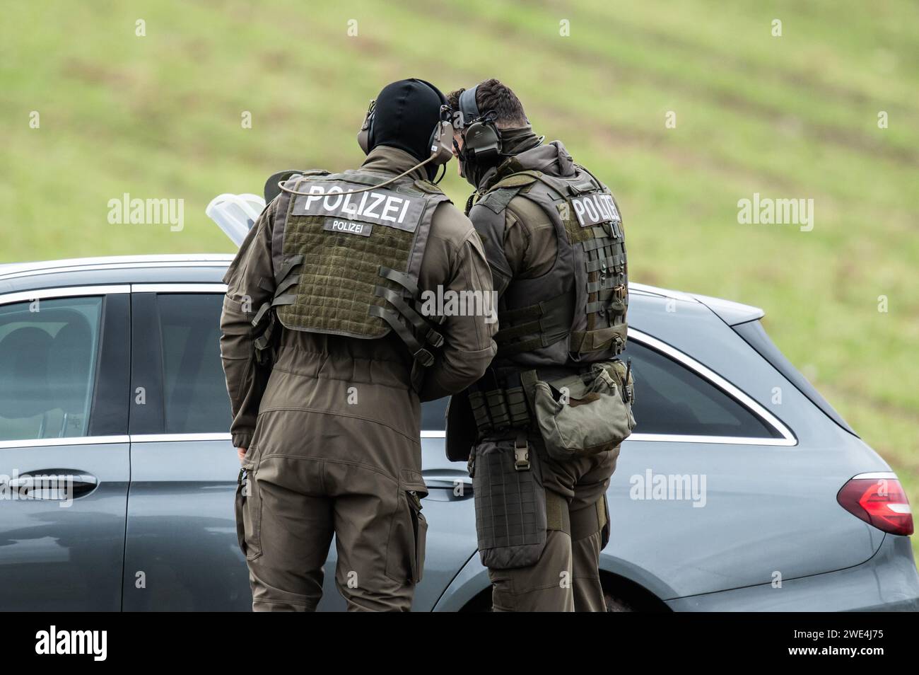 Unterkirnach, Deutschland. Januar 2024. Mitglieder einer Special Police Task Force (SEK) diskutieren über ein ziviles Polizeifahrzeug. Da die Räumung zu eskalieren drohte, setzt die Polizei derzeit ein großes Kontingent in Unterkirnach (Bezirk Schwarzwald-Baar) ein. Laut einer Aussage widersetzte sich ein Mann der Räumung am Dienstagmorgen und drohte, sein Haus niederbrennen zu lassen. Die Polizei sperrte das Haus ab und evakuierte umliegende Gebäude. Quelle: Silas Stein/dpa/Alamy Live News Stockfoto