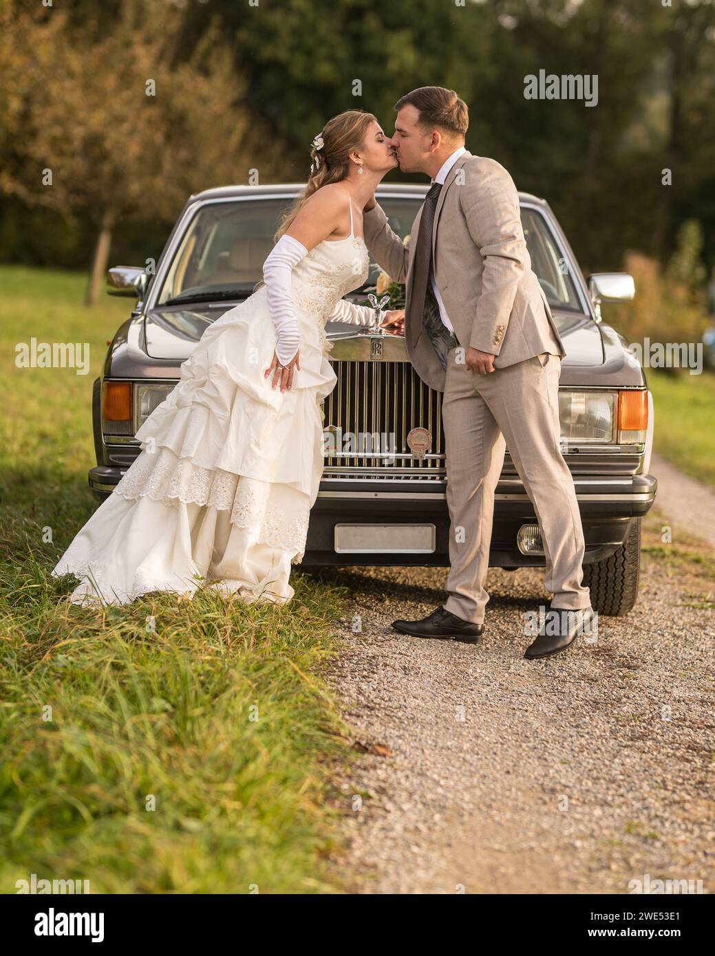 Lustige, ungewöhnliche, stilvolle, originelle Fotos mit Rollenumkehr eines jungen, attraktiven Brautpaares mit wunderschönen Veteranenautos in der Natur. Stockfoto