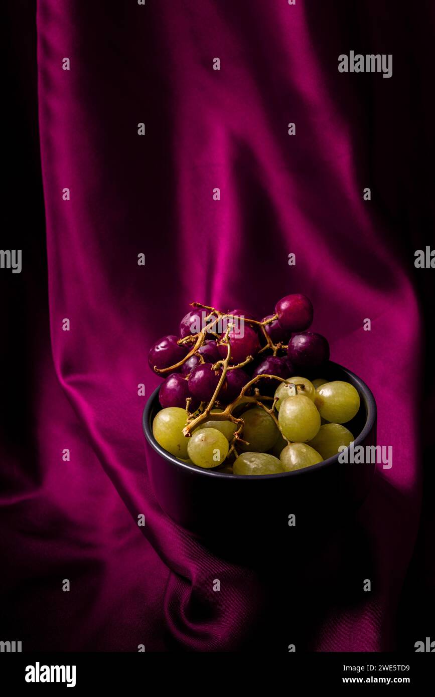 Schüssel mit Trauben mit seidenem Textil als Hintergrund Stockfoto