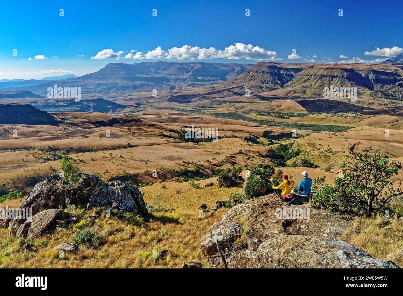 Mann und Frau, die auf Felsen sitzen und Little Berg, Pavian Rock, Didima, Cathedral Peak, Drakensberg, KWA Zulu Natal, UNESCO-Welterbe Stockfoto