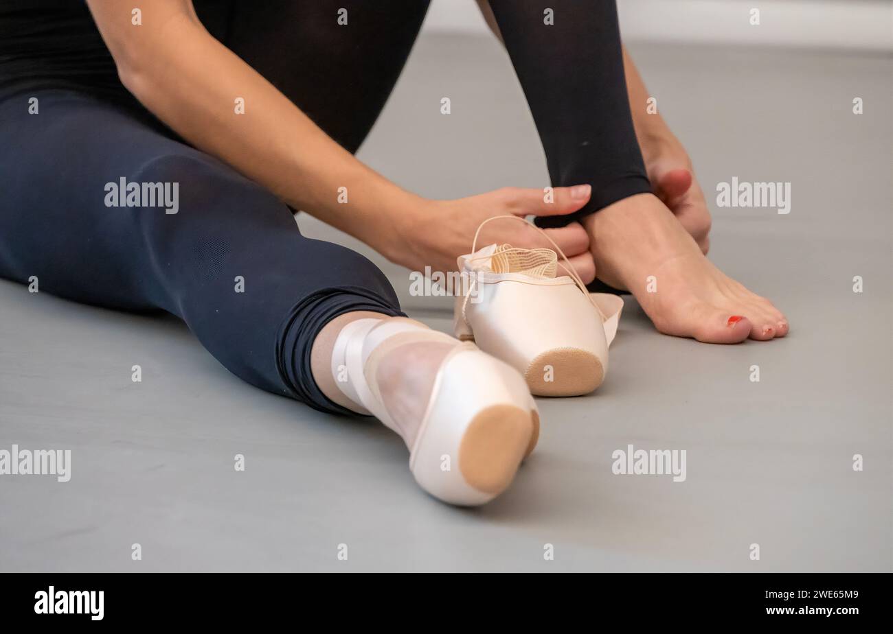 Balletttänzerin, die Schuhe zu Beginn der Übung im Tanzstudio anzieht. Stockfoto