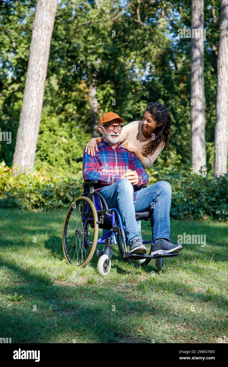 Lächelnder Freiwilliger mit Händen auf den Schultern des älteren Mannes im Park Stockfoto