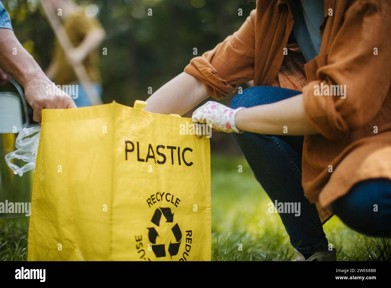 Frau, die Plastikmüll-Recyclingbeutel auf Bewährung legt Stockfoto