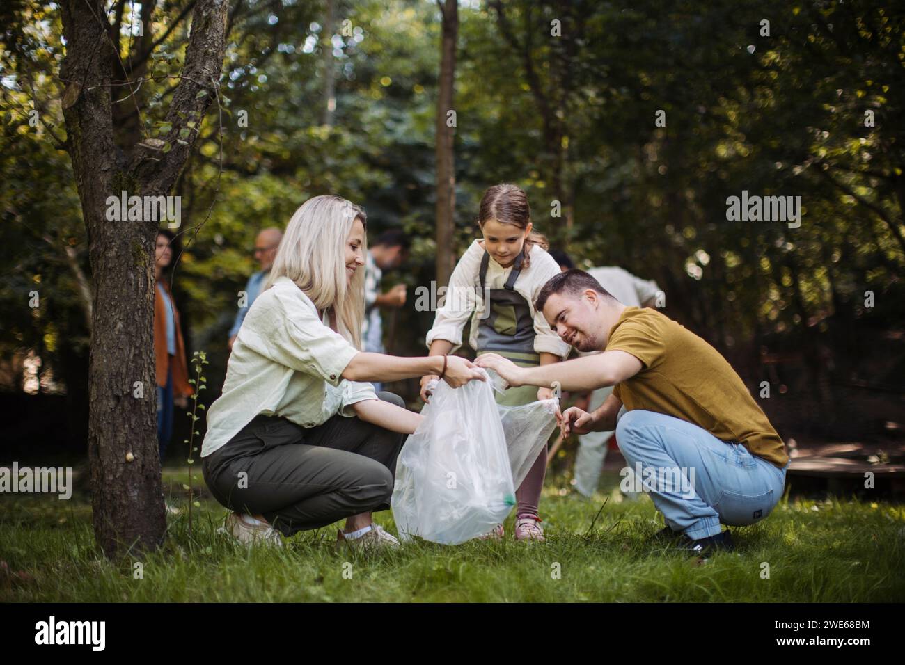 Sozial inkludierende Gruppe von Freiwilligen, die Kunststoffabfälle im öffentlichen Park sammeln Stockfoto