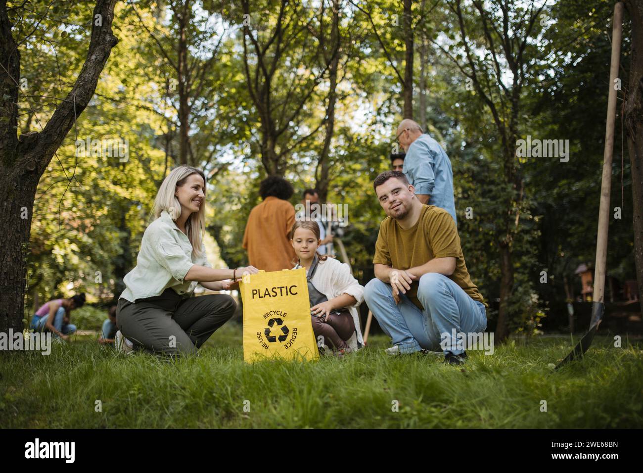 Sozial inkludierende Gruppe von Freiwilligen, die Kunststoffabfälle in Recyclingbeutel legen Stockfoto