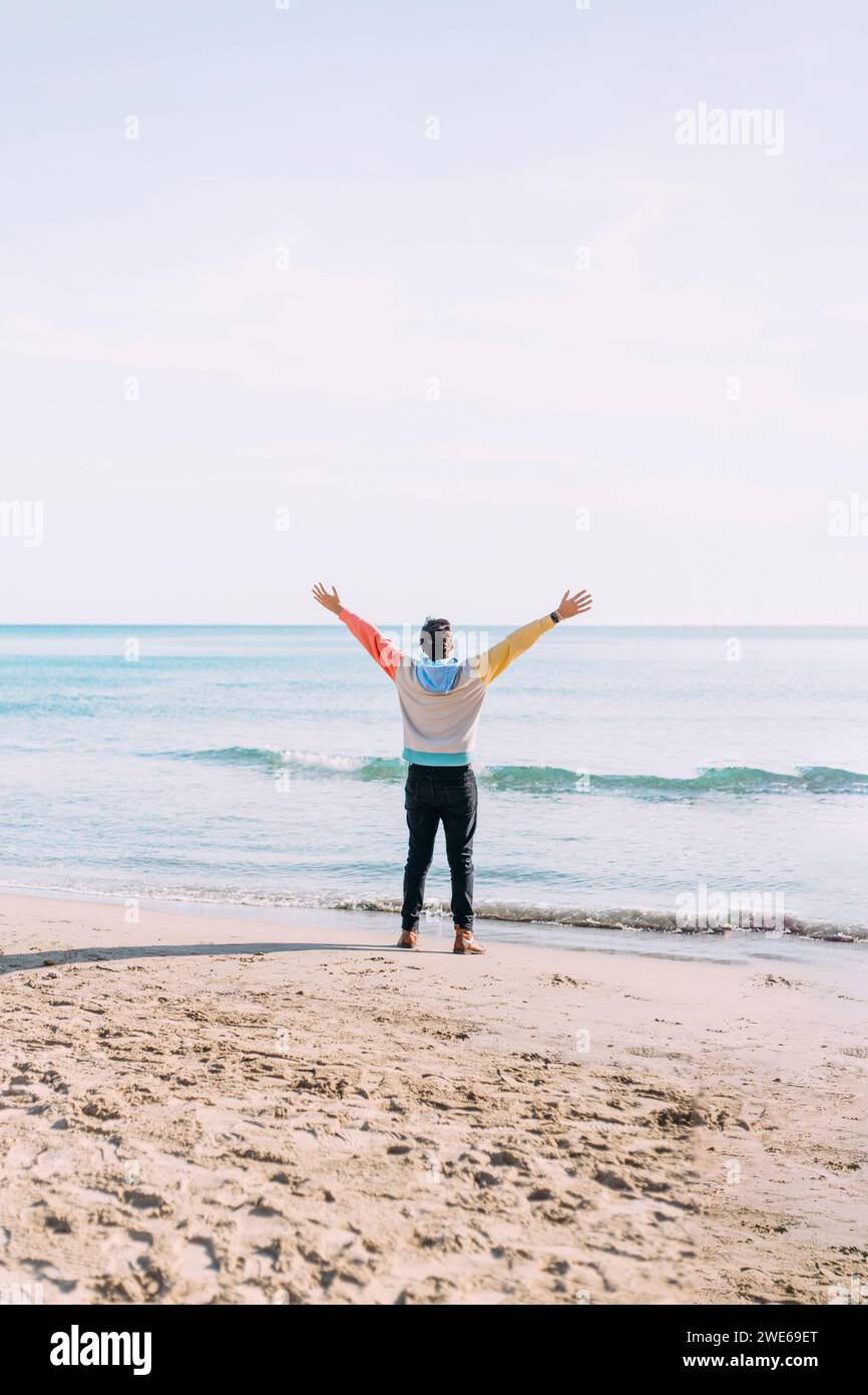 Mann mit stehenden Armen am Strand Stockfoto