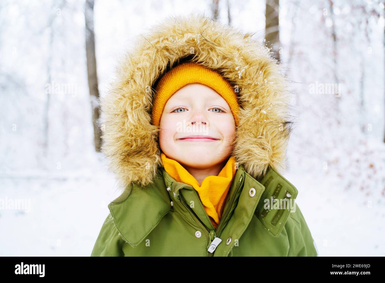 Lächelnder Junge, der im Winter einen Parkamantel trägt Stockfoto