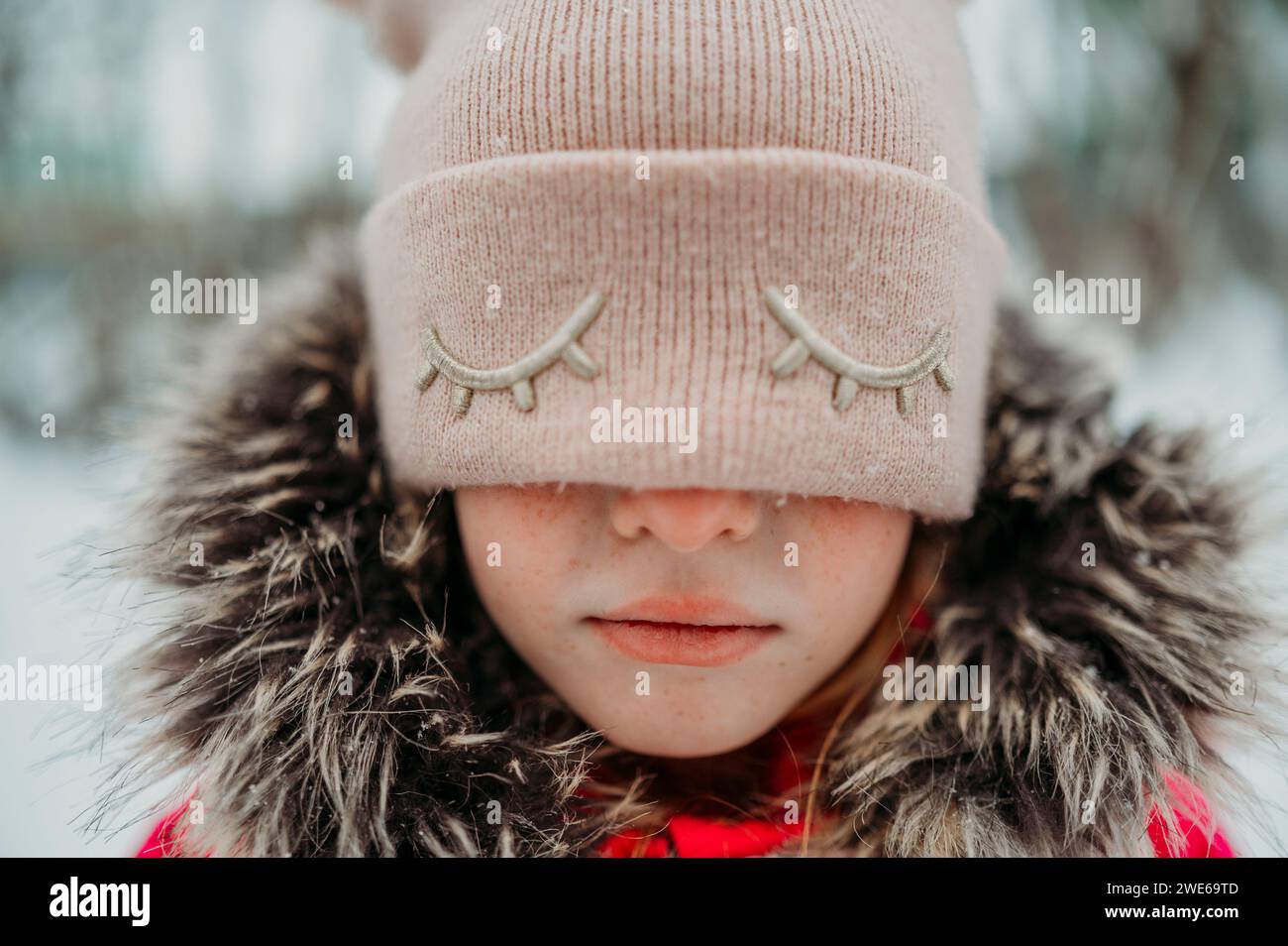 Trauriges Mädchen, das Augen mit rosa Strickmütze bedeckt Stockfoto