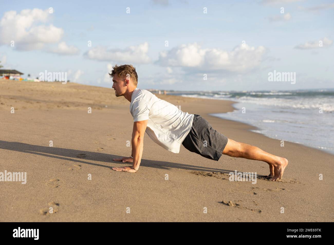 Junger Mann trainiert am Strand auf Sand Stockfoto