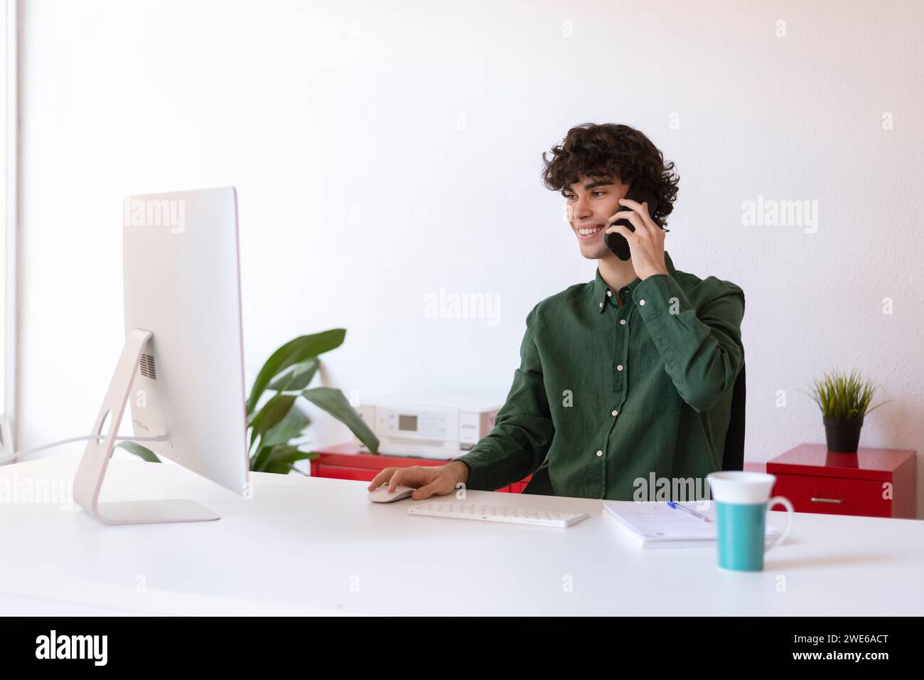 Lächelnder Geschäftsmann, der im Home Office Multitasking macht Stockfoto