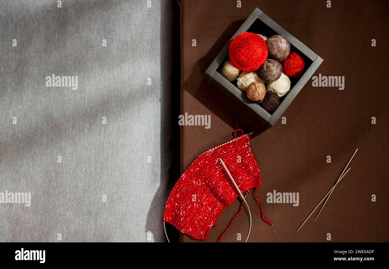 Kugeln aus buntem Garn in Box mit Nadeln auf dem Tisch Stockfoto
