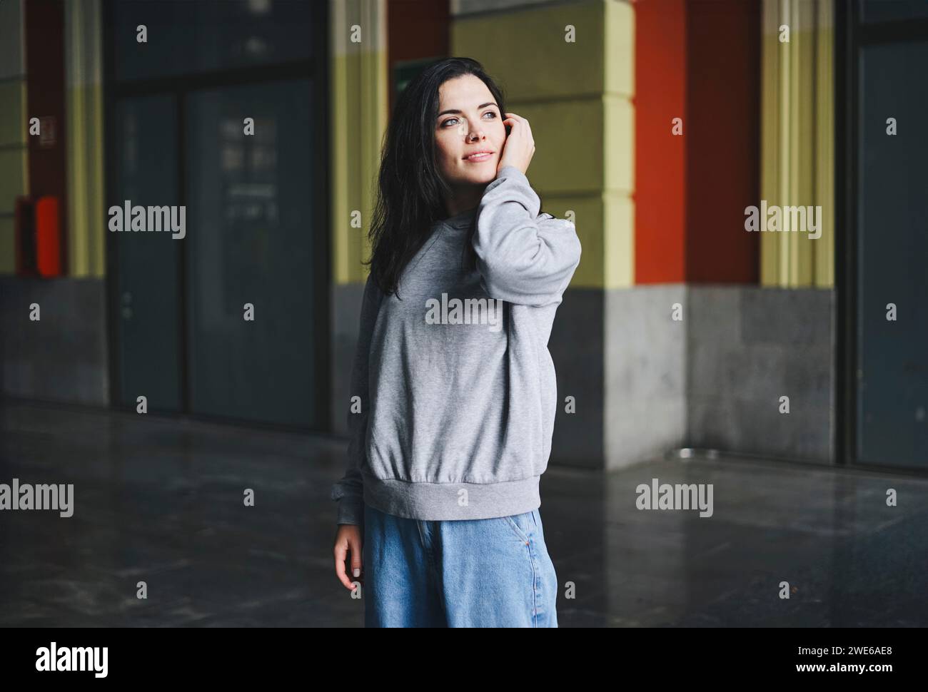 Lächelnde junge Frau träumend am urbanen Ort Stockfoto