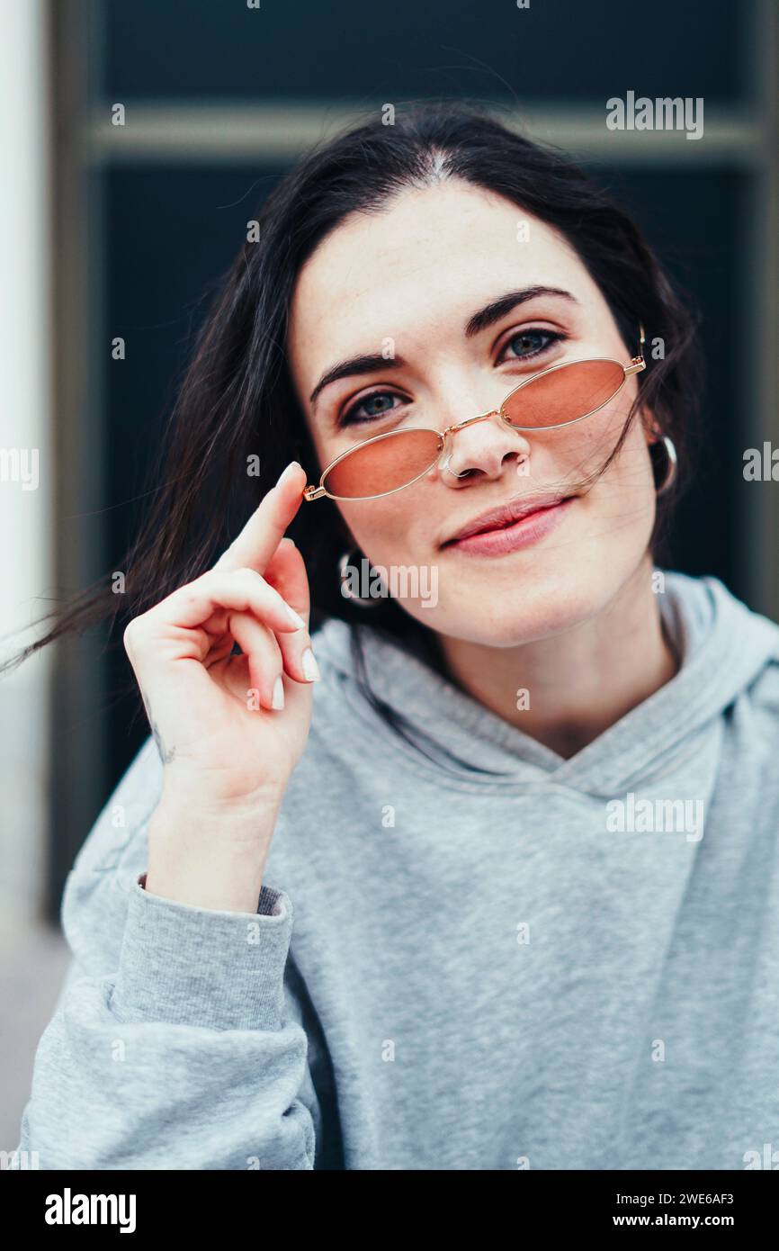 Lächelnde Frau, die Retro-Sonnenbrille berührt Stockfoto