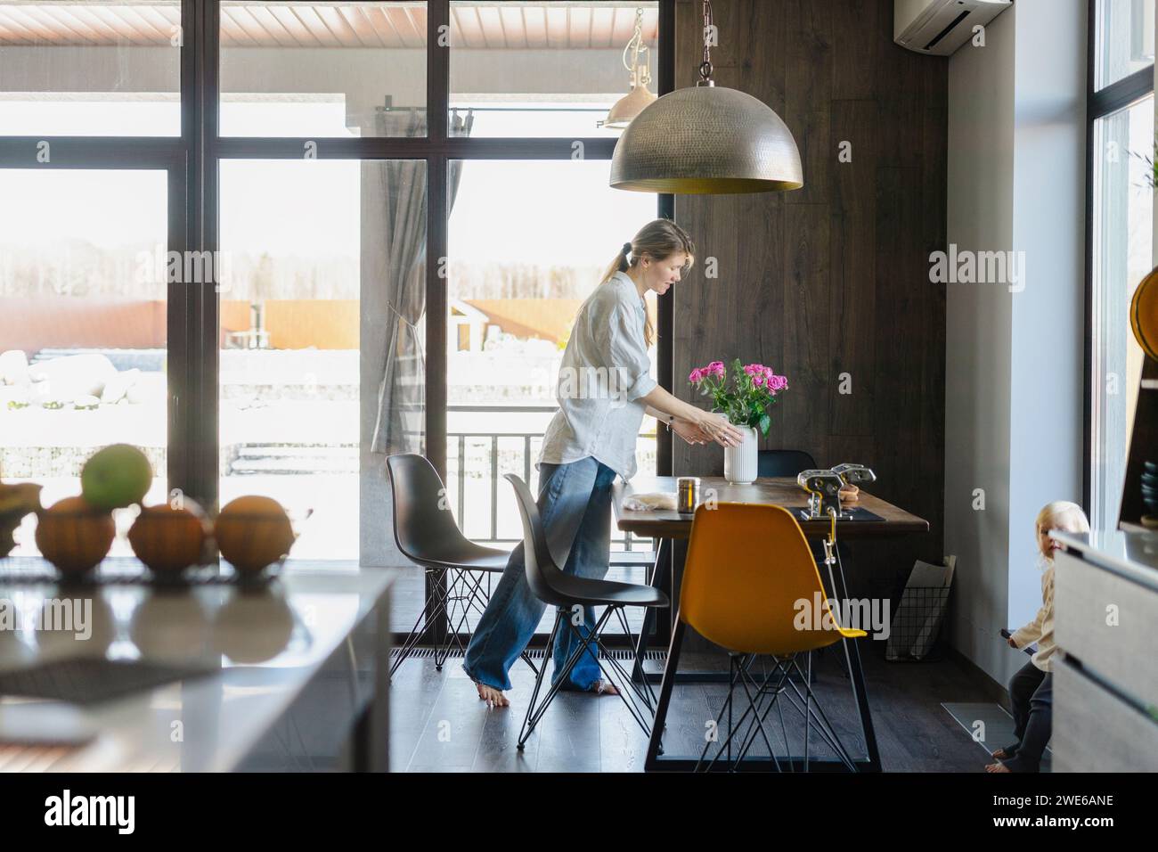 Frau arrangierte Blumenvase und stellte zu Hause einen Esstisch auf Stockfoto
