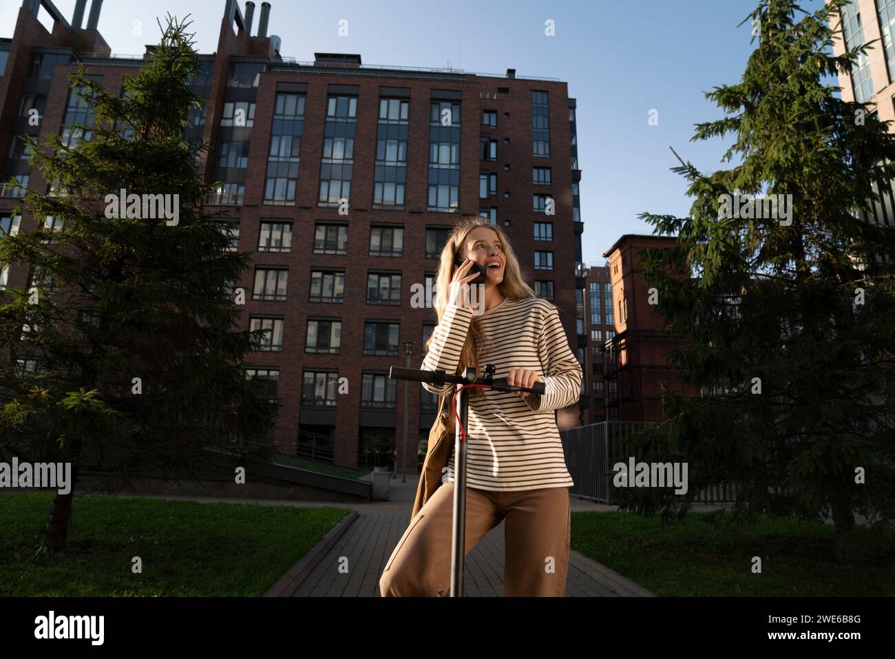 Frau, die mit einem elektrischen Roller auf dem Handy spricht Stockfoto