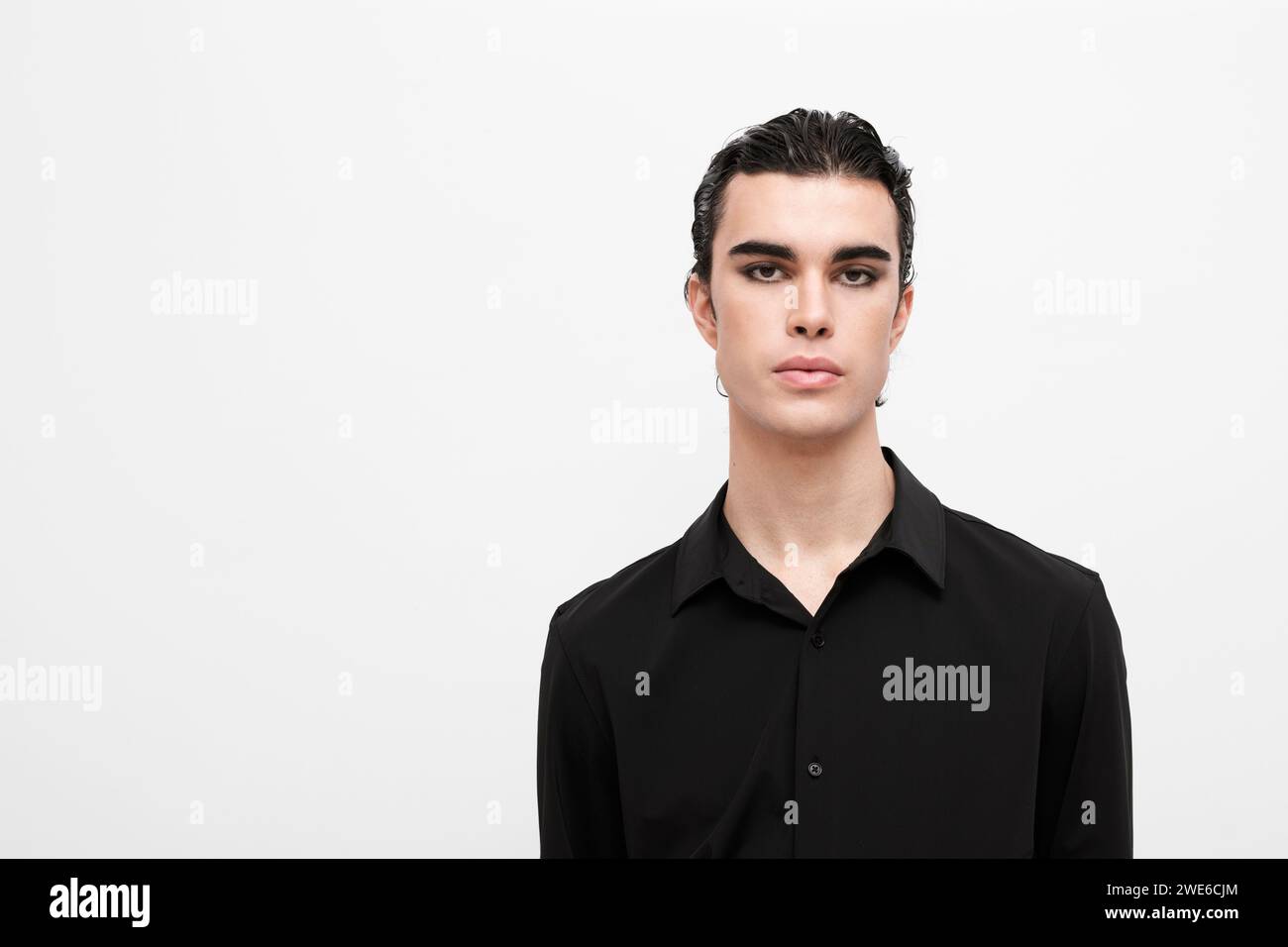 Junger Mann, der ein schwarzes Hemd auf weißem Hintergrund trägt Stockfoto