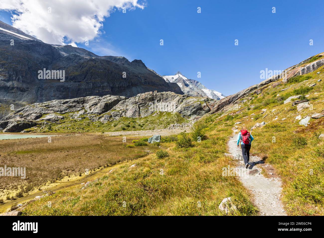 Frau, die auf der Straße in der Nähe der Berge in Großglockner, Österreich, läuft Stockfoto