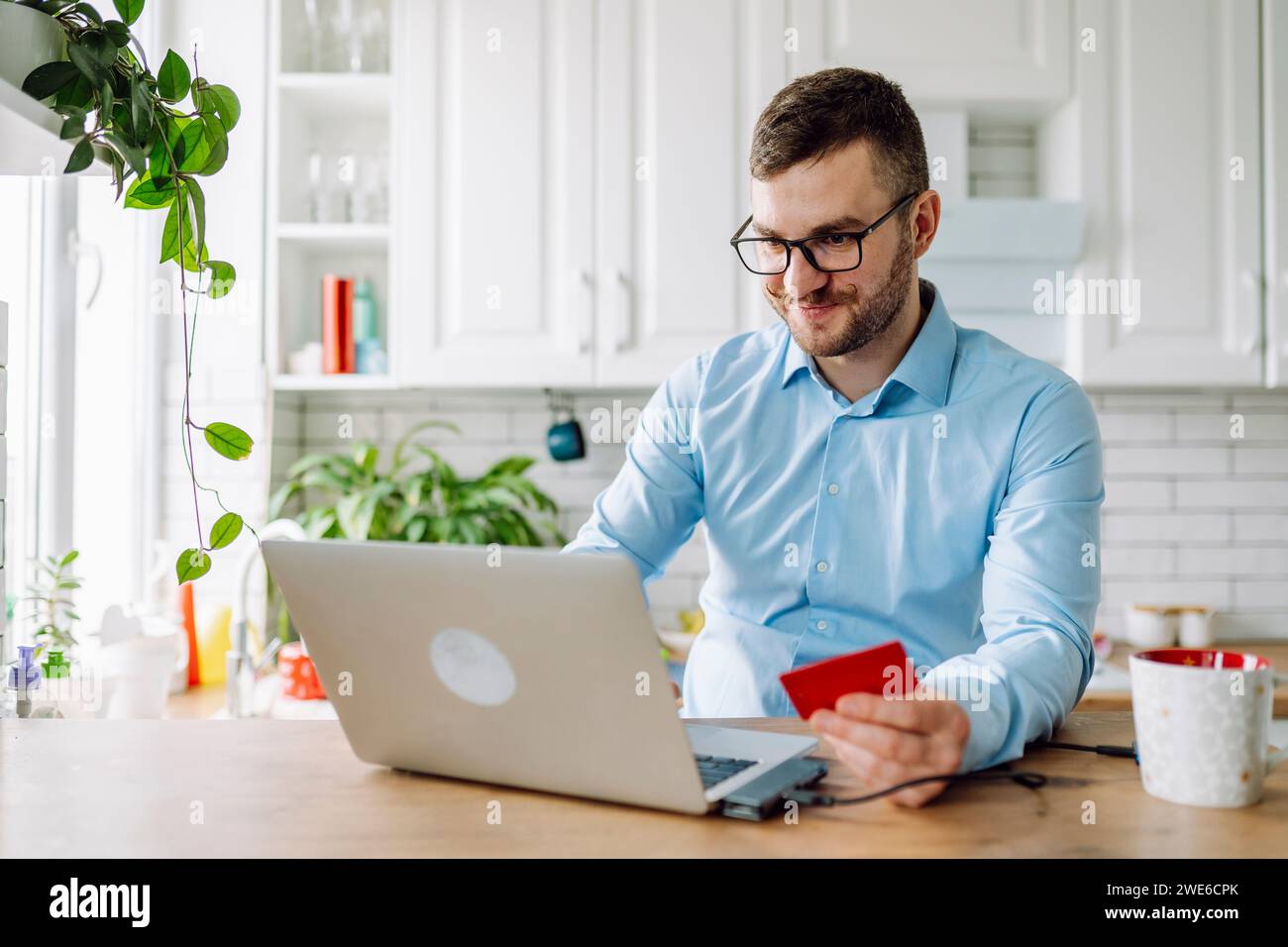 Lächelnder Freelancer, der zu Hause Kreditkartenkäufe auf einem Laptop macht Stockfoto