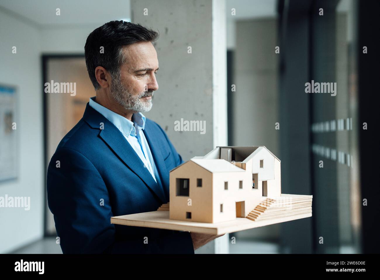 Architekt hält Holzmodellhaus im Bürokorridor Stockfoto