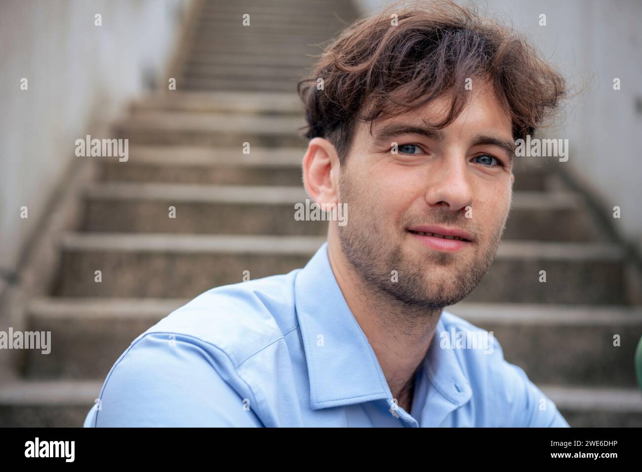 Junger, gutaussehender Mann, der auf Stufen sitzt Stockfoto