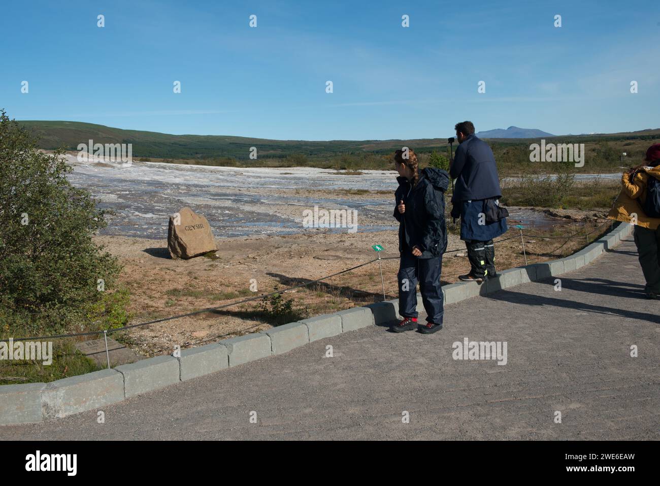 Ein paar Touristenattraktionen, die Markierung für den ruhenden Großen Geysir Islands an den östlichen Hängen des Laugarfjalls. Stockfoto