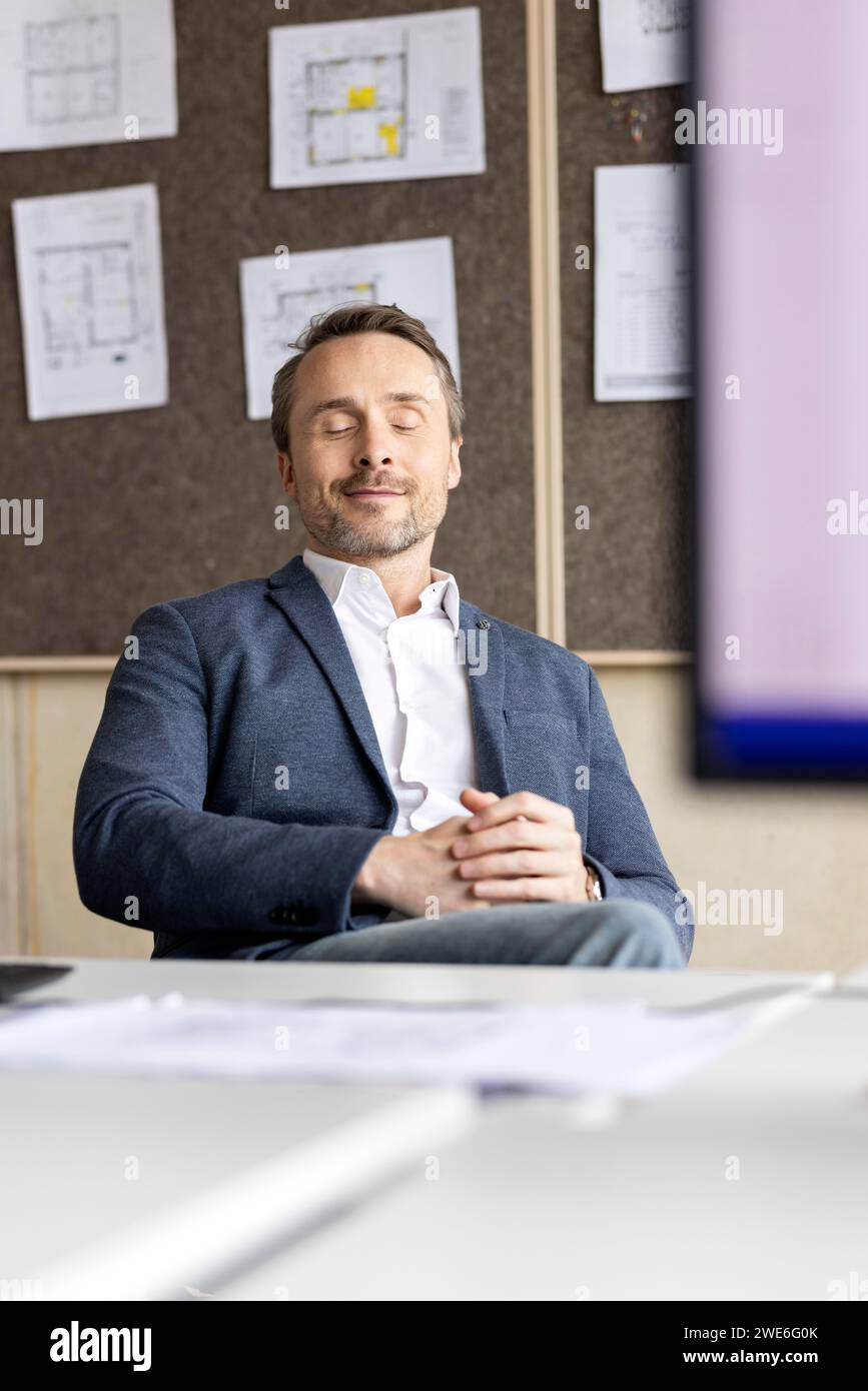 Geschäftsmann mit geschlossenen Augen am Arbeitsplatz Stockfoto