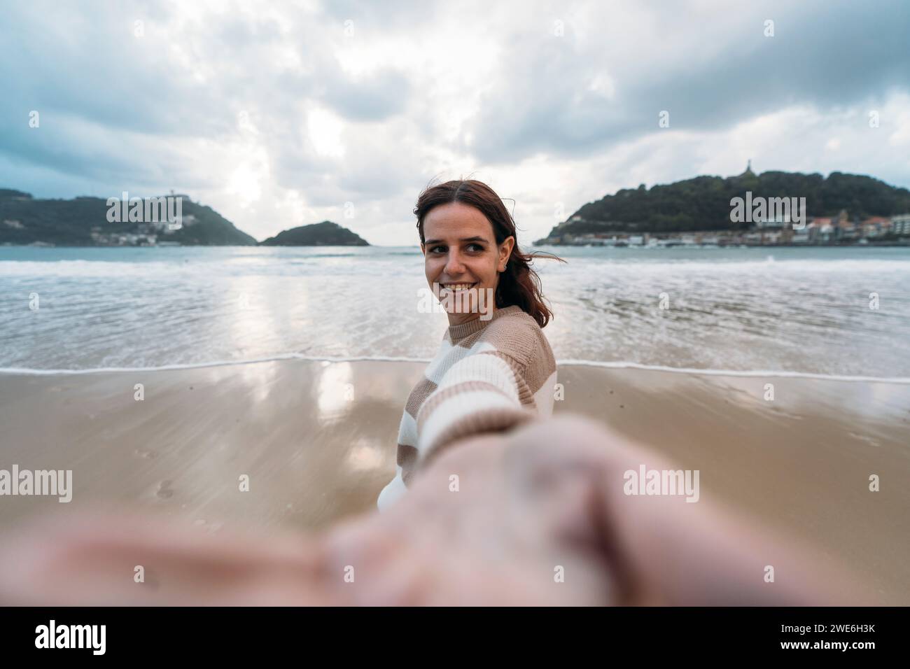 Junge Frau am Ufer von Playa de la Concha unter bewölktem Himmel Stockfoto Junge Frau am Ufer von Playa de la Concha unter bewölktem Himmel Stockfoto