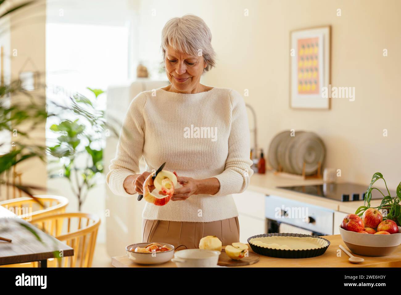 Reife Frau, die zu Hause Äpfel mit einem Messer schält Stockfoto