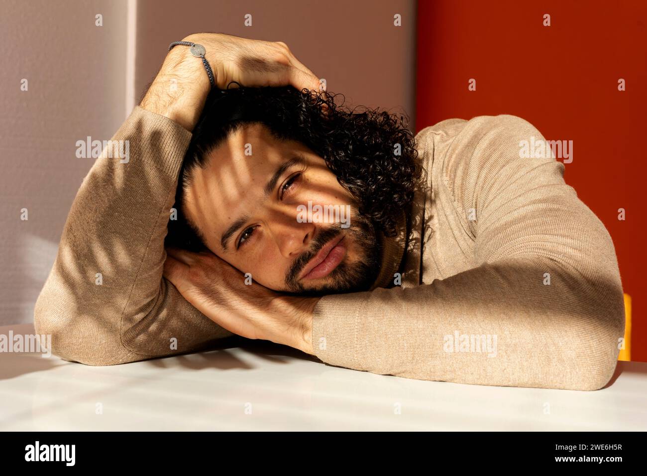 Mann mit Kopf in der Hand, der sich auf den Tisch lehnt Stockfoto